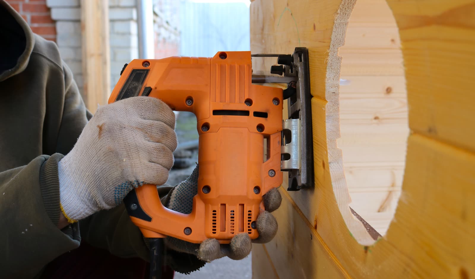 A worker uses an electric jigsaw to cut a circle o — the kind of handyman work vetted local pros handle in Sarasota, FL