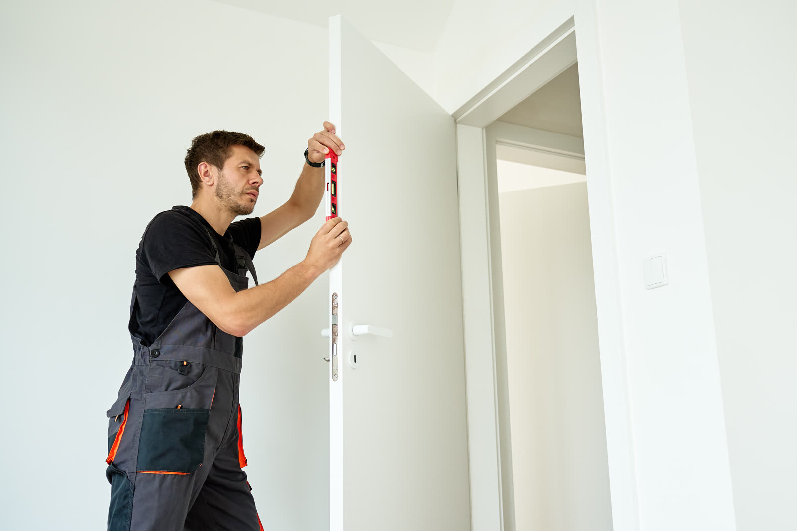 Carpenter checking door alignment with spirit leve — the kind of handyman work vetted local pros handle in Sarasota, FL