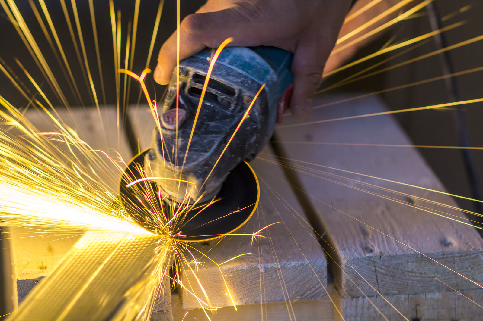 Close up of worker hands cutting metal with grinde — the kind of handyman work vetted local pros handle in Sarasota, FL