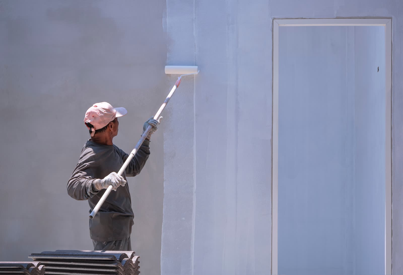 Construction worker painting primer white color on — the kind of handyman work vetted local pros handle in Sarasota, FL