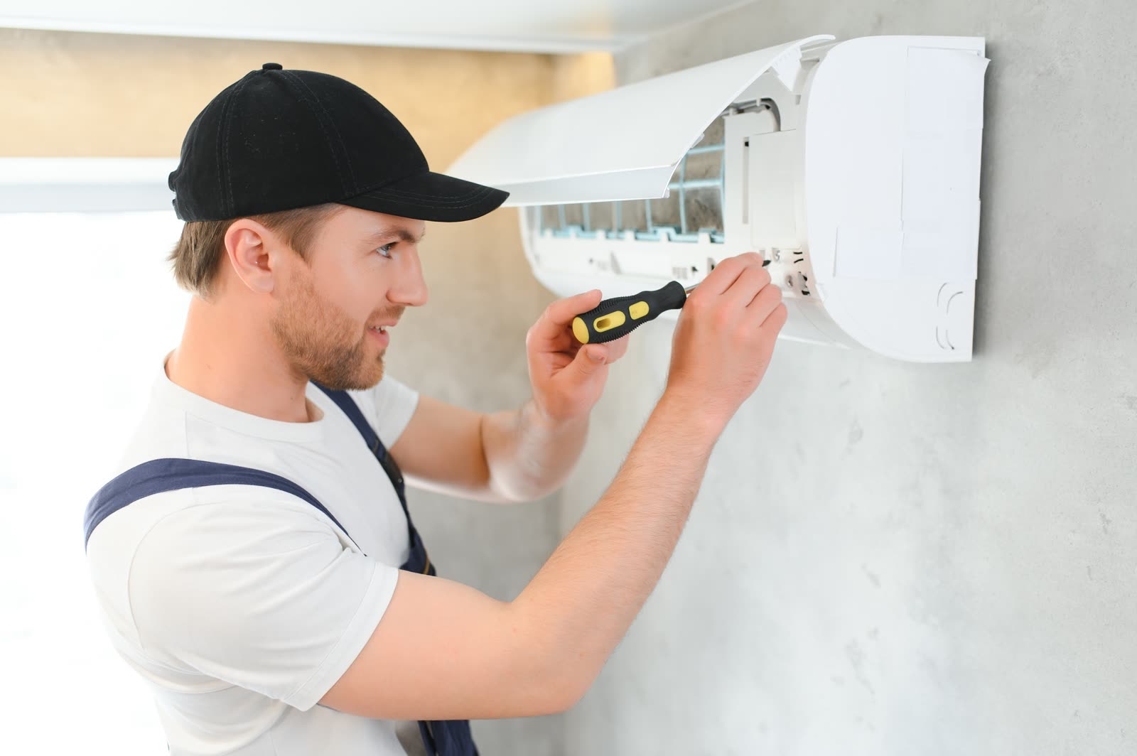 Handsome young man electrician installing air cond — the kind of handyman work vetted local pros handle in Sarasota, FL