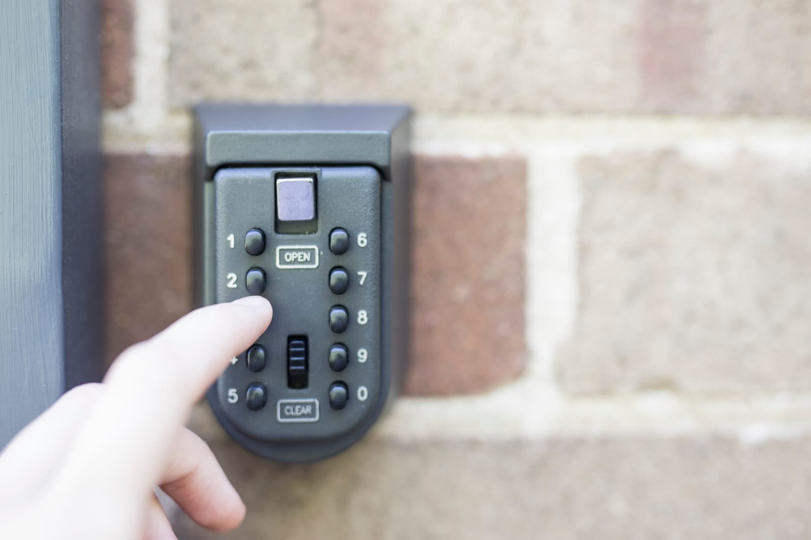 Key lockbox with keypad mounted on a brick wall