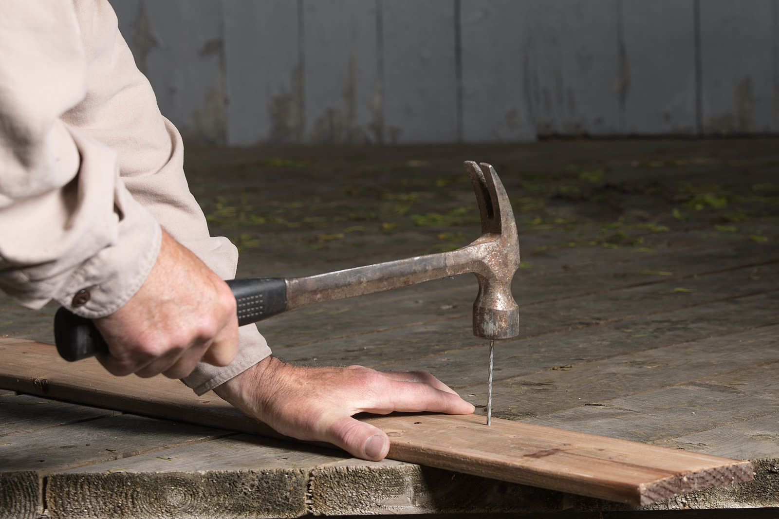 Male hand of a carpenter holding a hammer to hit a — the kind of handyman work vetted local pros handle in Sarasota, FL