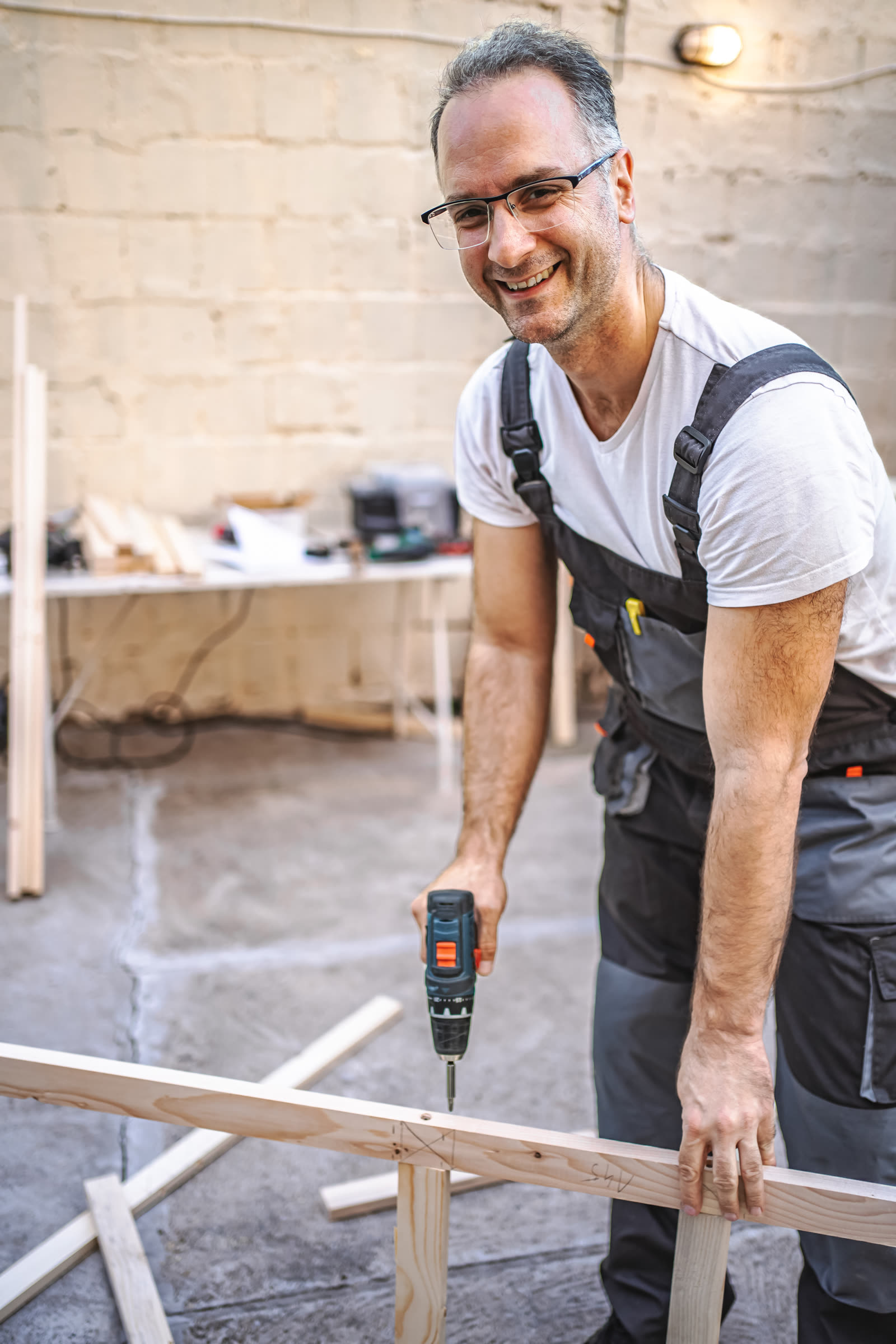 Mature male carpenter using electric screwdriver o — the kind of handyman work vetted local pros handle in Sarasota, FL