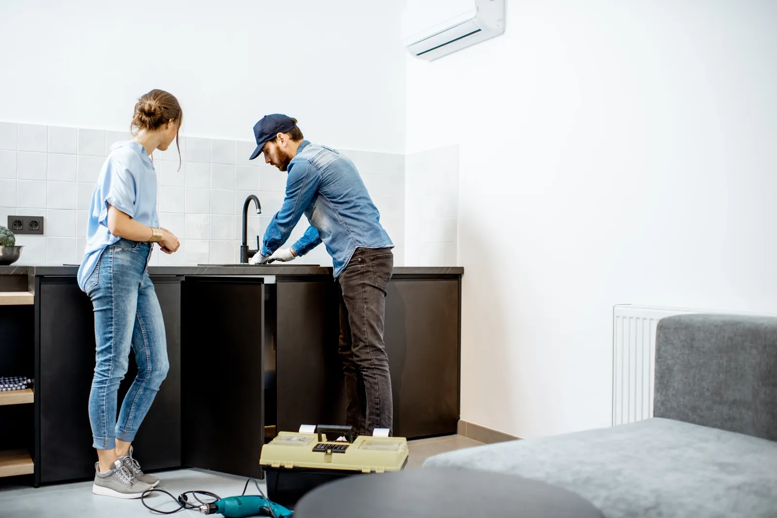 Plumber repairing kitchen faucet with woman — the kind of handyman work vetted local pros handle in Sarasota, FL