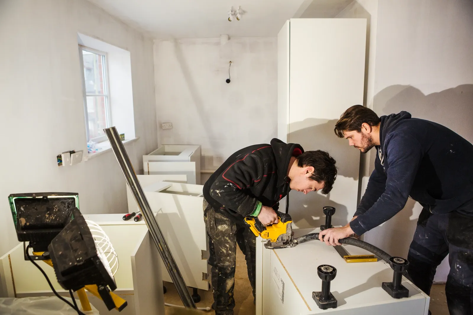Two builders cutting plasterboard for a kitchen — the kind of handyman work vetted local pros handle in Sarasota, FL
