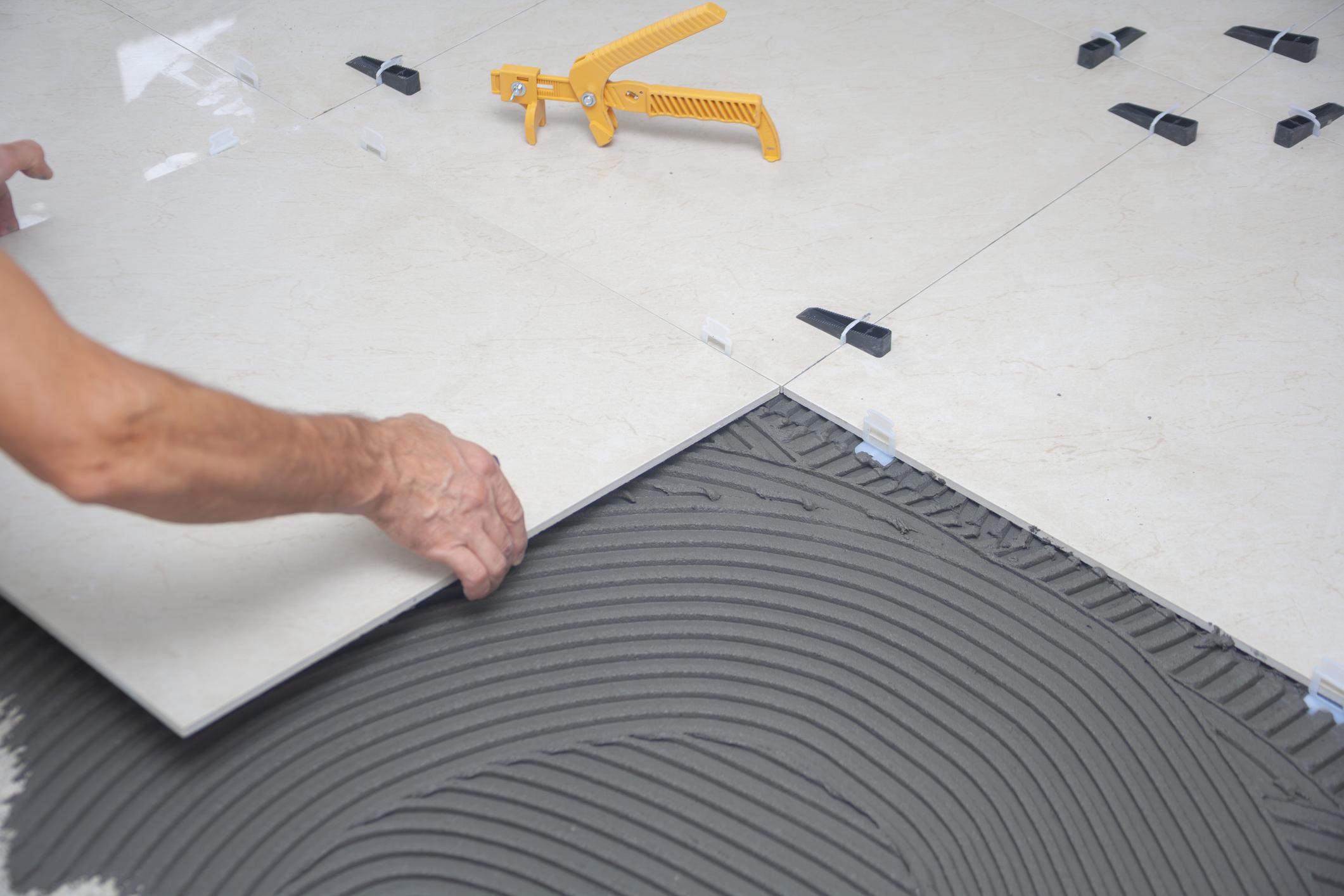Professional installation of bathroom floor tiles with leveling and adhesive