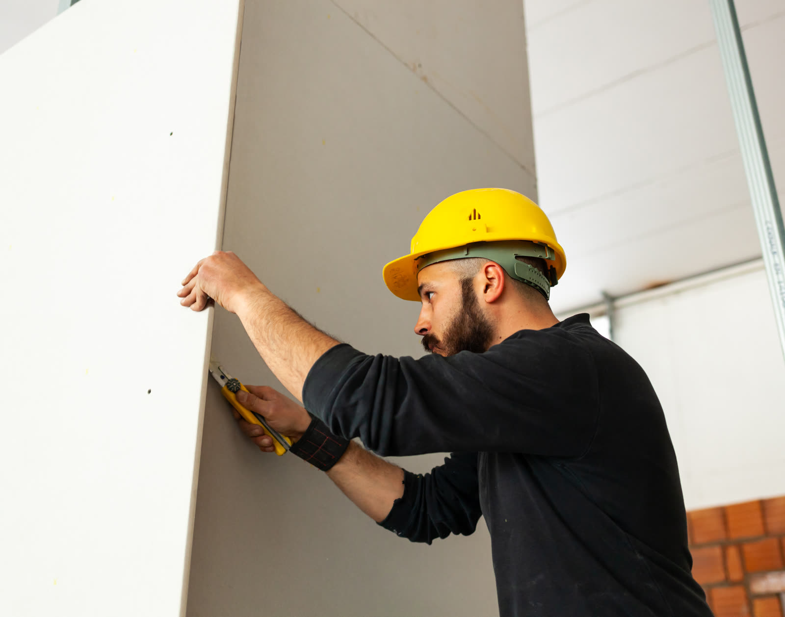 Worker builds a plasterboard wall — the kind of handyman work vetted local pros handle in Sarasota, FL
