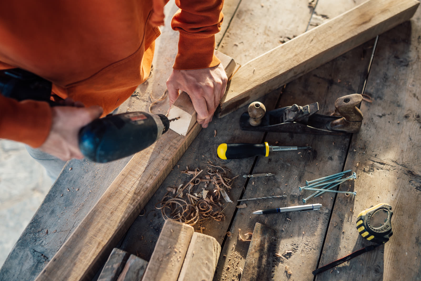 A worker drills a hole in wooden bar with drill — the kind of handyman work vetted local pros handle in Sarasota, FL
