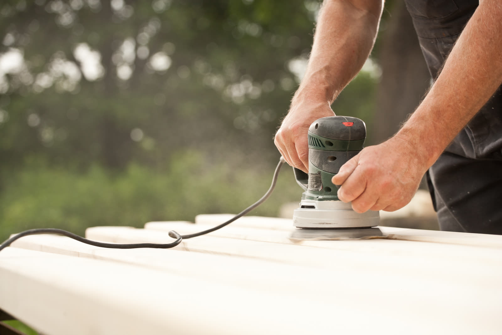 Closeup of a handyman carpenters hand sanding a w — the kind of handyman work vetted local pros handle in Sarasota, FL