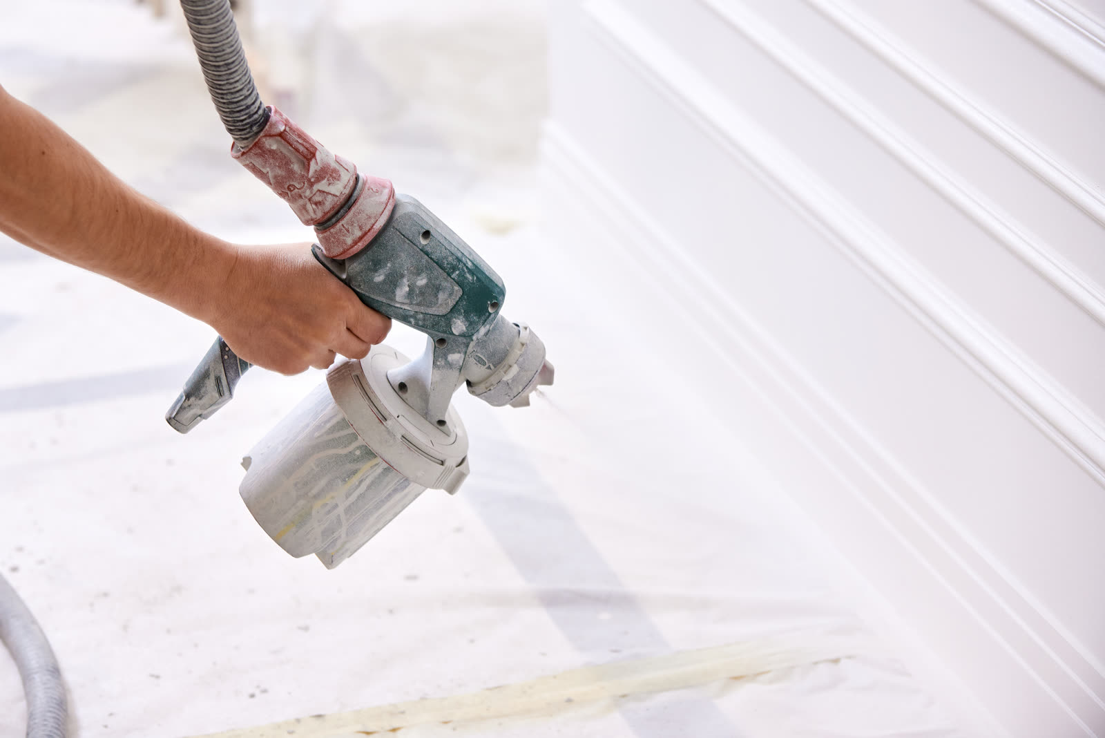 worker painting wall with spray gun in white color — Painting (Interior & Exterior) in Sarasota, FL